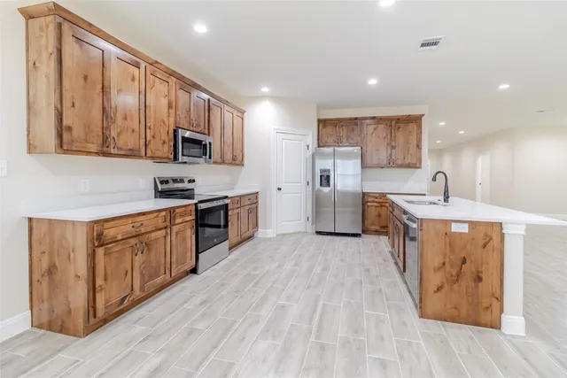a large kitchen with stainless steel appliances granite countertop a large stove top oven a sink dishwasher and white cabinets with wooden floor