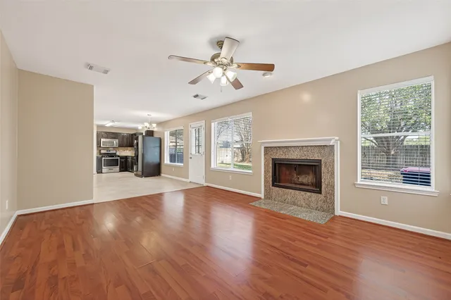 a view of an empty room with wooden floor fireplace and a window