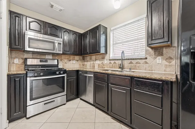 a kitchen with stainless steel appliances granite countertop a sink stove and microwave