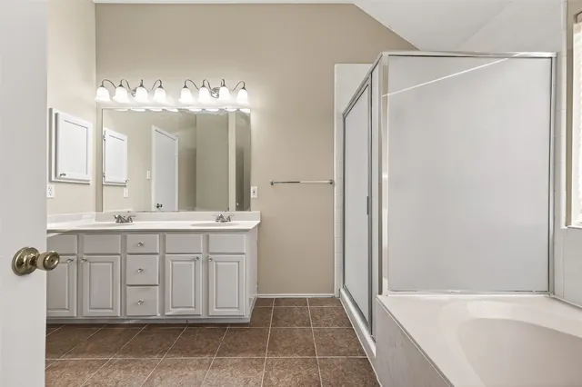 a bathroom with a double vanity sink mirror and a bathtub