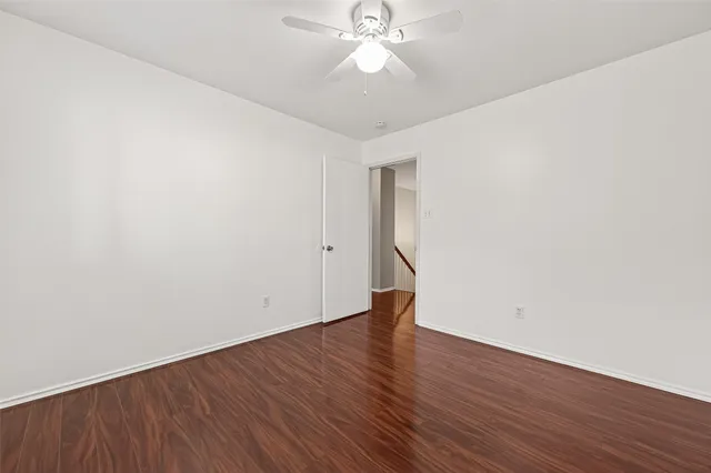 an empty room with wooden floor and fan