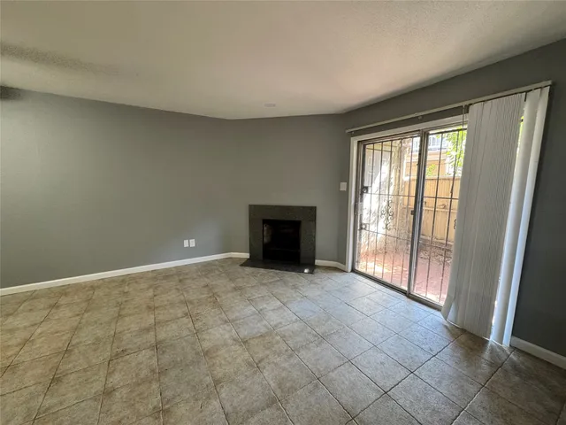 a view of an empty room with a fireplace and a window