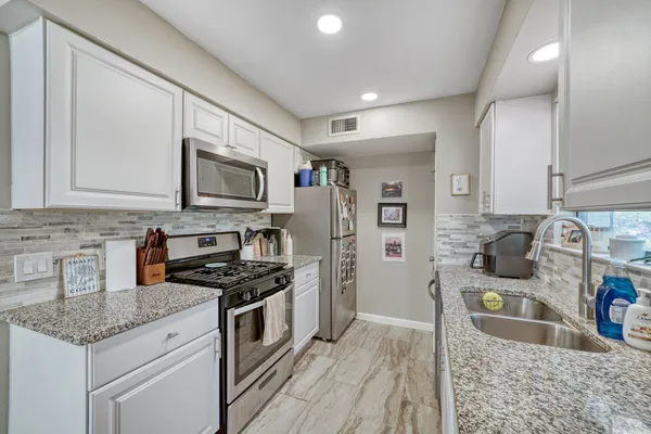 a kitchen with stainless steel appliances granite countertop a sink stove and refrigerator