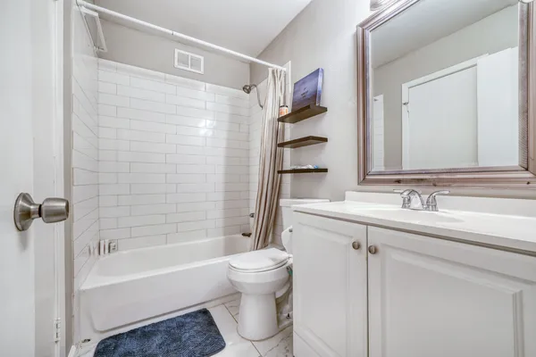 a bathroom with a bathtub shower sink vanity and toilet