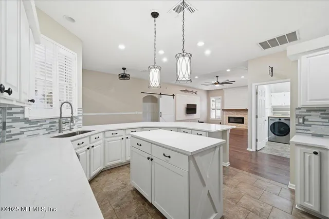 a large white kitchen with kitchen island a sink stainless steel appliances and cabinets