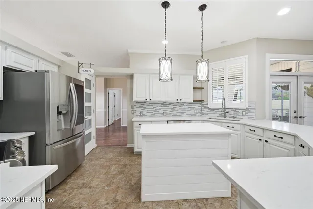 a view of an empty room with a kitchen and a window