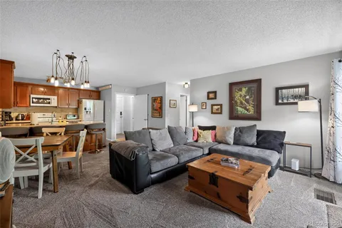 a living room with furniture a chandelier and kitchen view