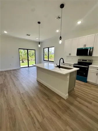a kitchen with kitchen island granite countertop a sink cabinets and wooden floor