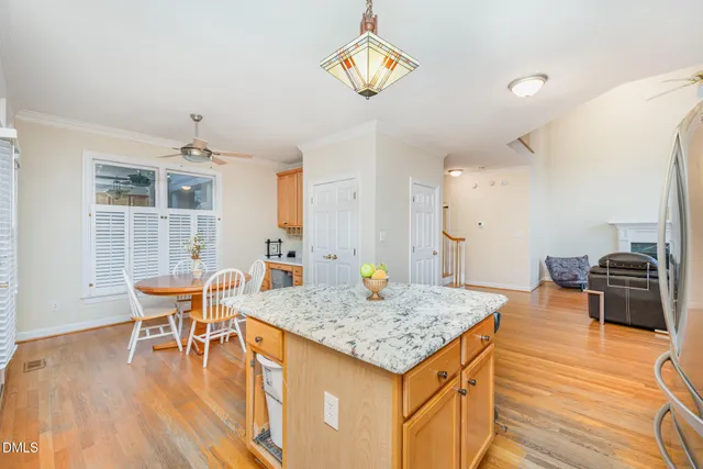 a kitchen with stainless steel appliances granite countertop a stove top oven a sink a dining table and chairs with wooden floor