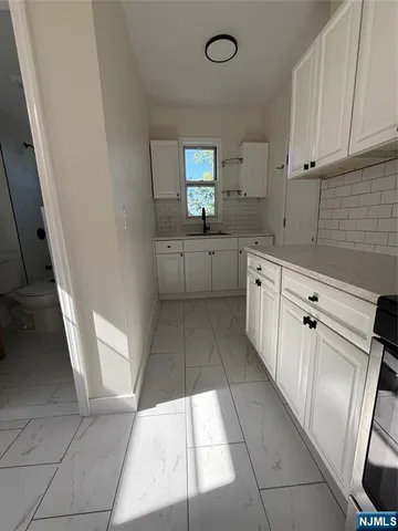 a large white kitchen with sink and washing machine