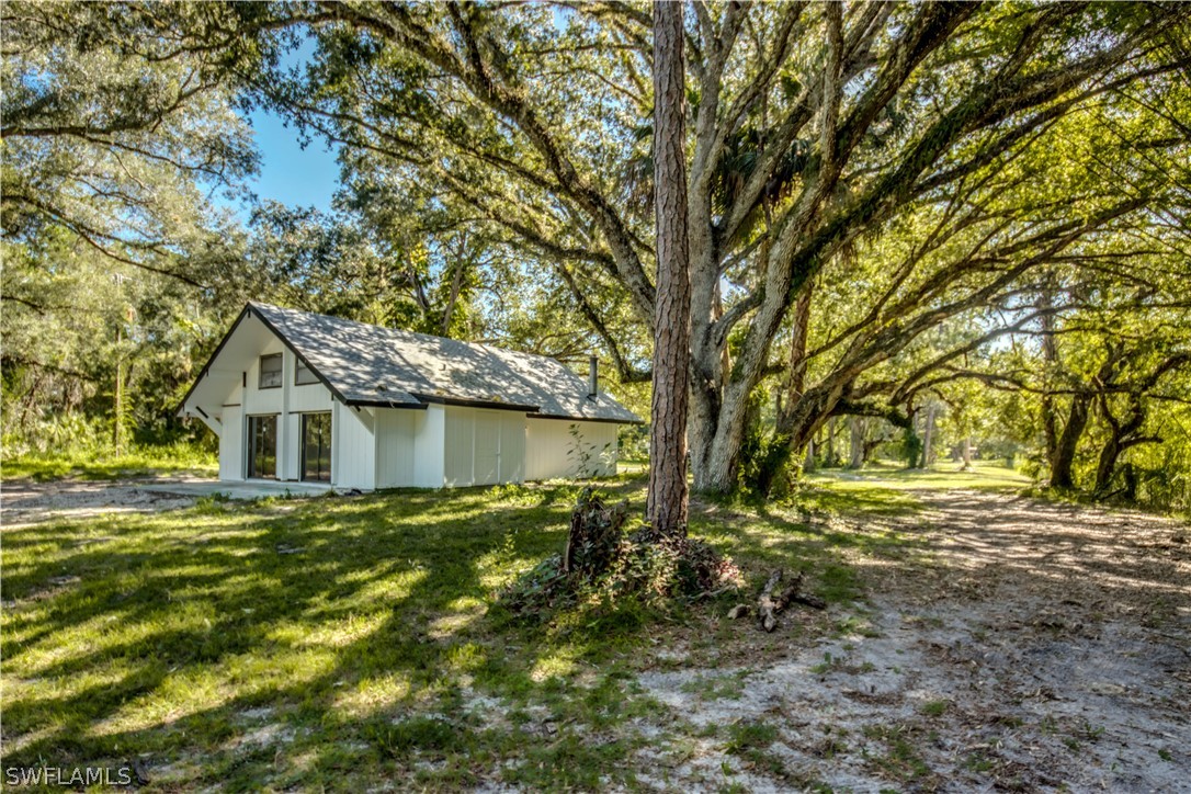 275 Trader Road Fort Denaud, FL 33935 - Photo 30 of 32 a backyard of a house with large trees and outdoor seating