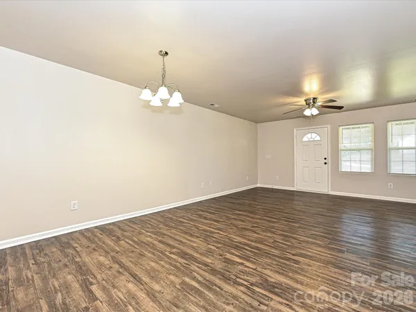 wooden floor in an empty room with a chandelier fan