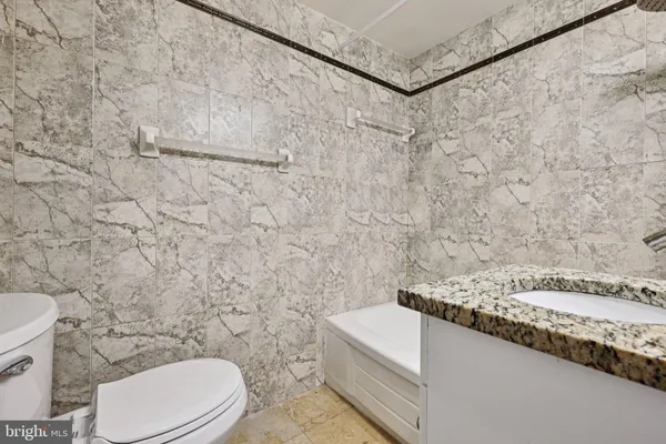 a bathroom with a granite countertop toilet and a sink