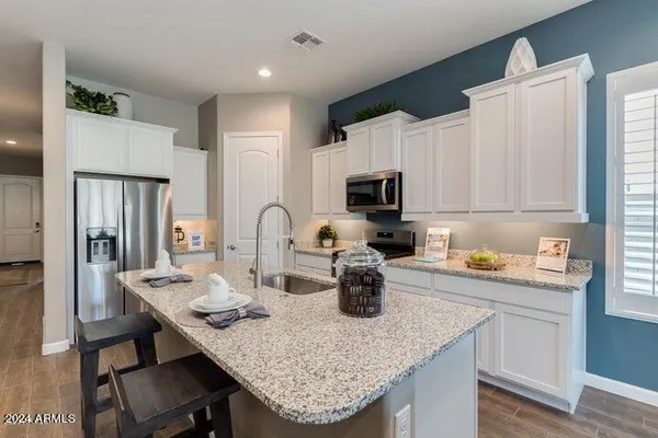 a kitchen with a sink dishwasher a refrigerator and white cabinets with wooden floor