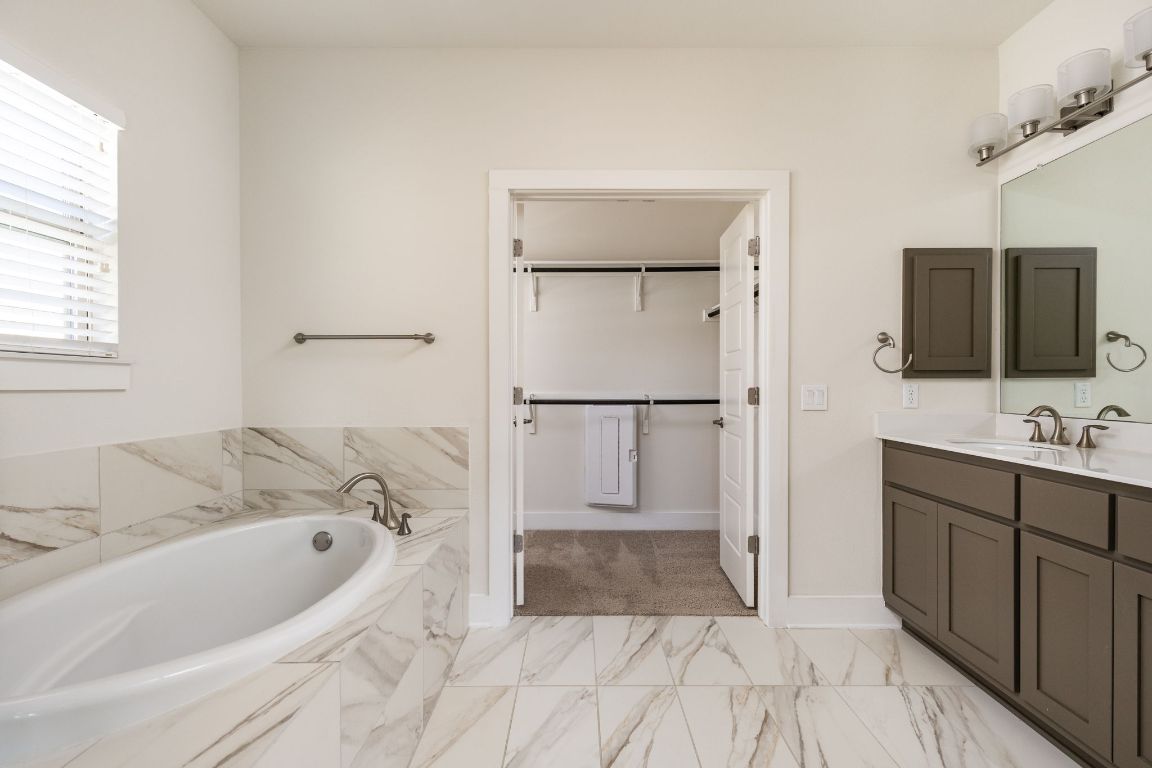2401 McBee Street Austin, TX 78723 - Photo 22 of 36 Full bath featuring a bath, vanity, a walk in closet, and light marble finish flooring