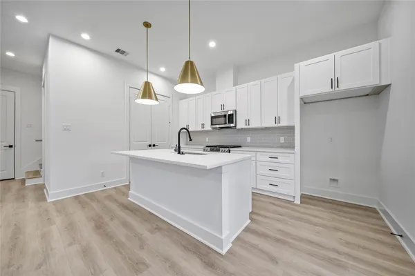 a kitchen with cabinets appliances and a wooden floor
