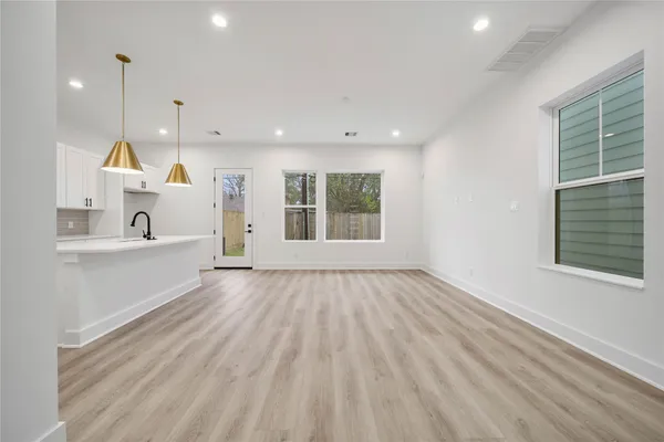 a view of an empty room with a window and wooden floor