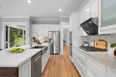 a kitchen with granite countertop stainless steel appliances a sink stove top oven and cabinets