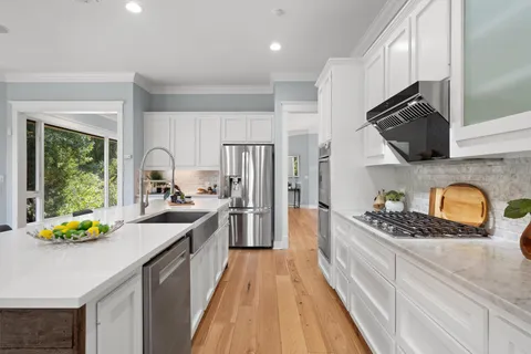 a kitchen with granite countertop stainless steel appliances a sink stove top oven and cabinets