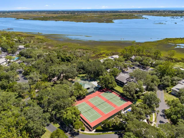 a view of a tennis ground with large trees
