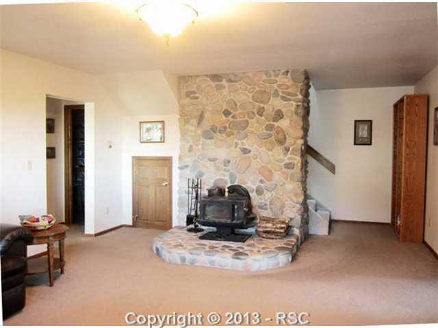 850 Oak Ridge Road Manitou Springs, CO 80829 - Photo 13 of 17 Family room with wood burning stove with real river rock hearth, back wall of garden level windows & Berber carpet.