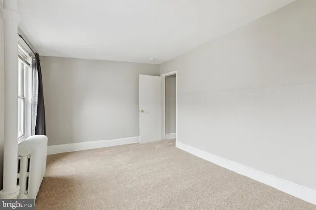 a view of an empty room with window and closet area