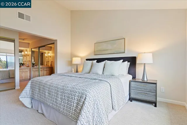 a bedroom with a bed a mirror and lamp