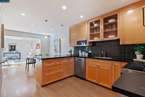 a kitchen with granite countertop kitchen island wooden floors and stainless steel appliances