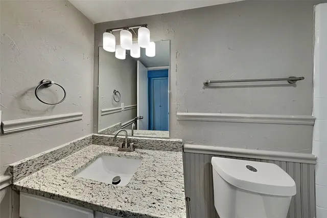 a bathroom with a granite countertop sink a toilet and a mirror