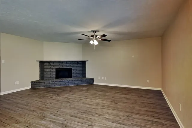 a view of an empty room with wooden floor and a fireplace
