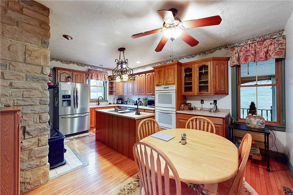 181 Rea Road Avella, PA 15312 - Photo 8 of 22 a kitchen with stainless steel appliances granite countertop a stove a refrigerator a oven a dining table and chairs with wooden floor