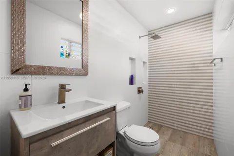 a bathroom with a sink a toilet a mirror and shower curtain