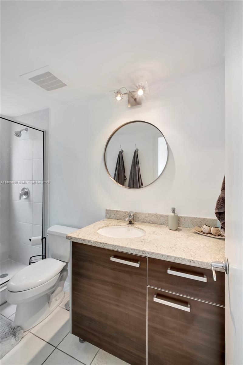 185 Southwest 7th Street, Unit 901 Miami, FL 33130 - Photo 14 of 35 a bathroom with a granite countertop toilet sink and mirror