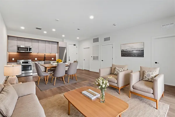 a living room with furniture kitchen view and a wooden floor