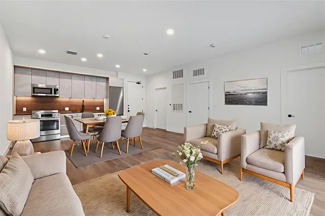 a living room with furniture kitchen view and a wooden floor