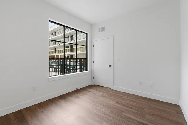 an empty room with wooden floor and windows