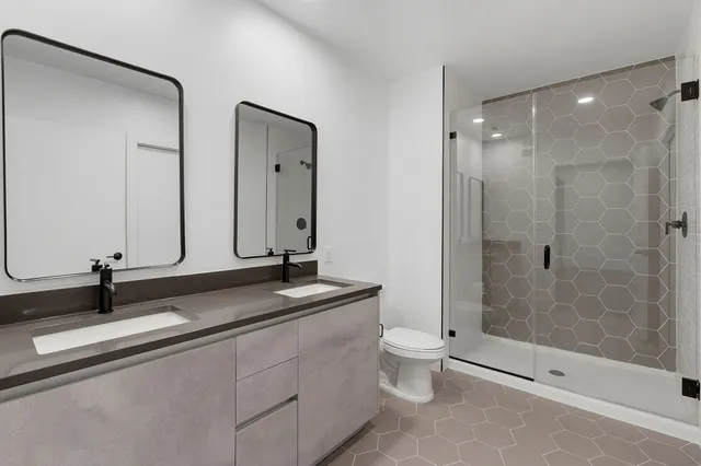 a bathroom with a double vanity sink toilet and shower