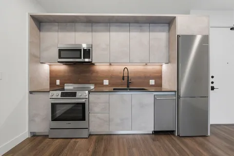 a kitchen with cabinets stainless steel appliances and wooden floor