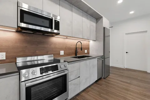 a kitchen with stainless steel appliances a stove a microwave oven cabinets and a wooden floor