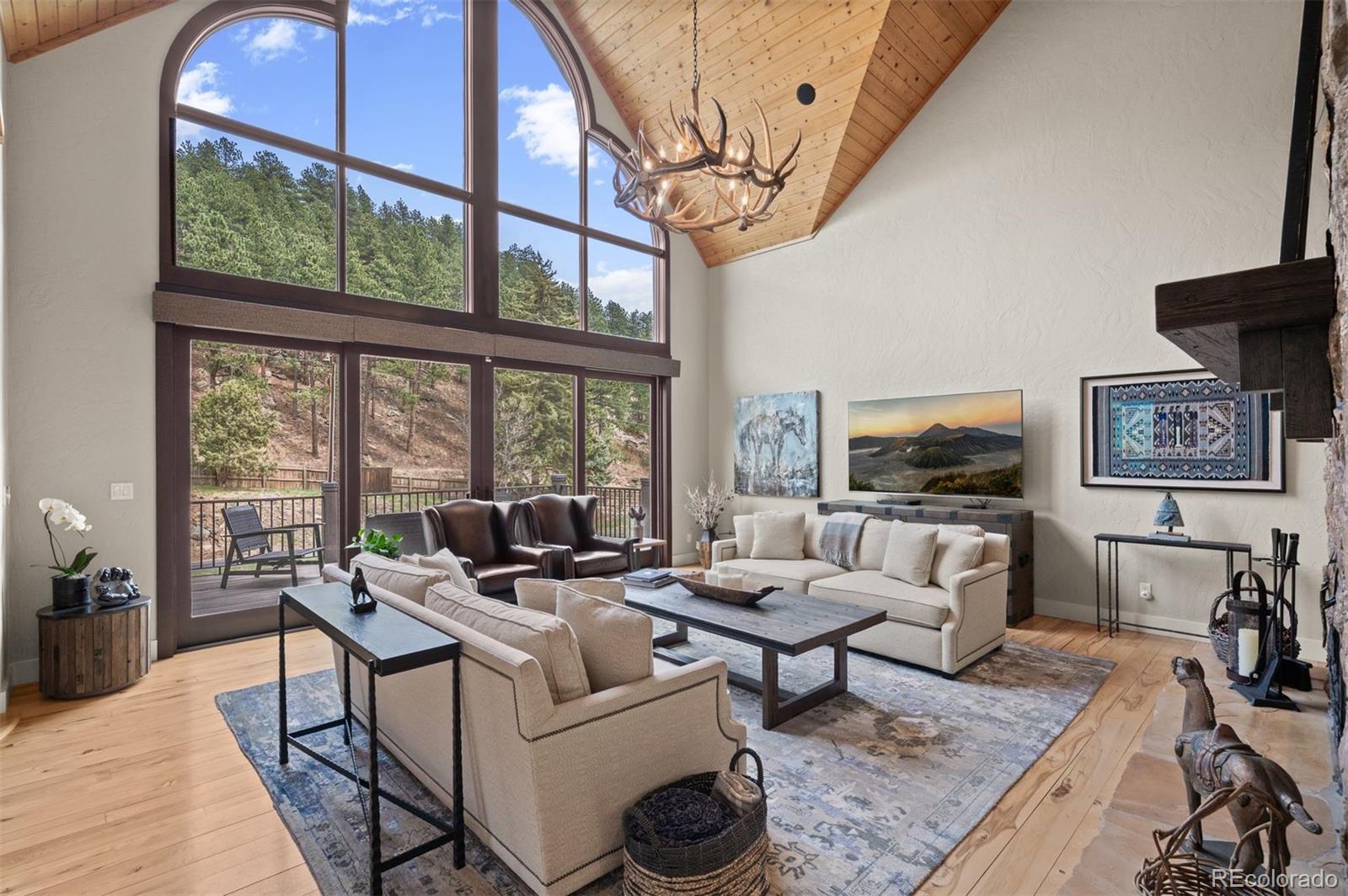 1733 Swede Gulch Road Evergreen, CO 80439 - Photo 12 of 50 a living room with furniture a flat screen tv and a large window