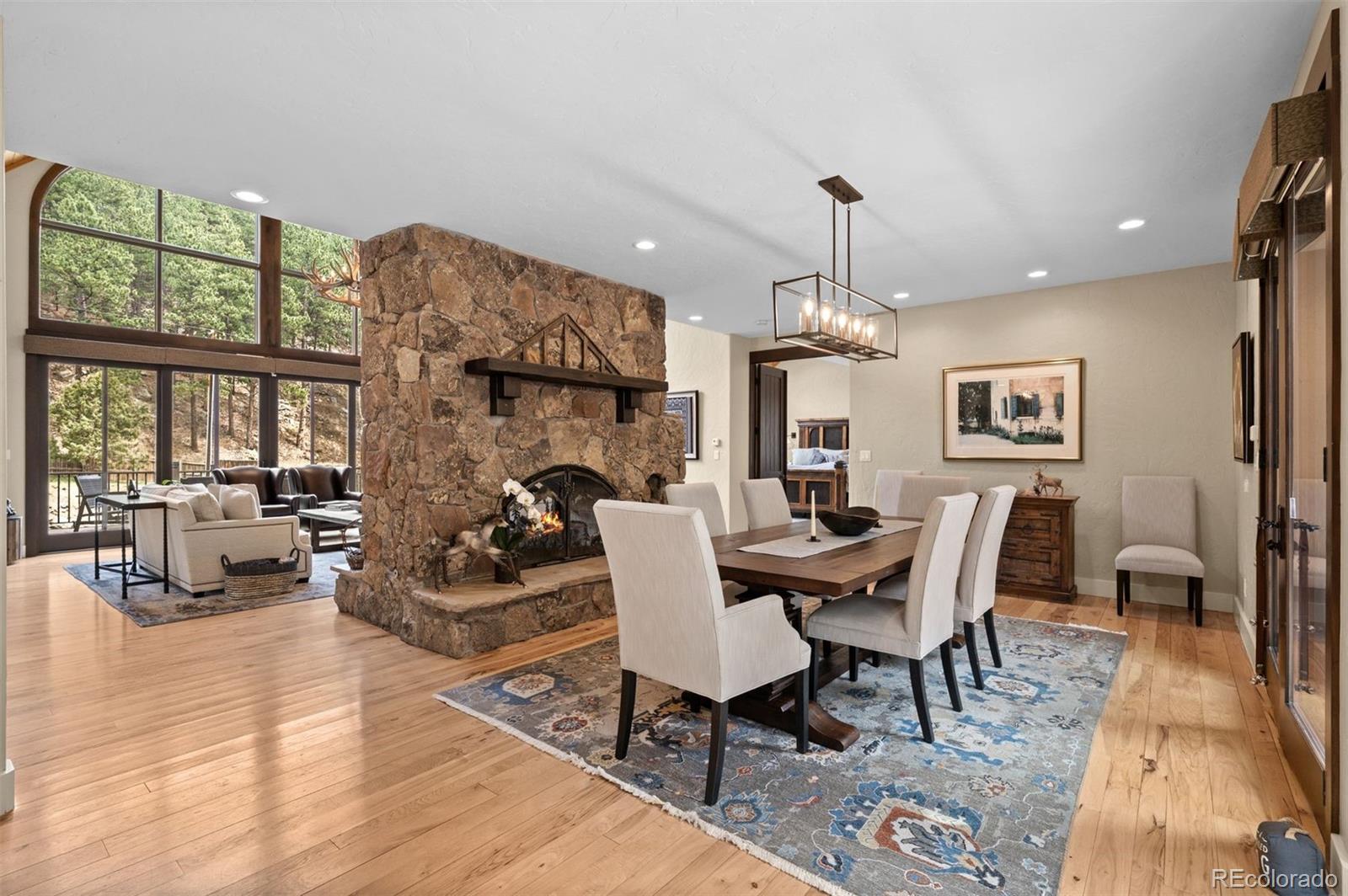 1733 Swede Gulch Road Evergreen, CO 80439 - Photo 15 of 50 a dining room with wooden floor a chandelier a wooden table and chairs
