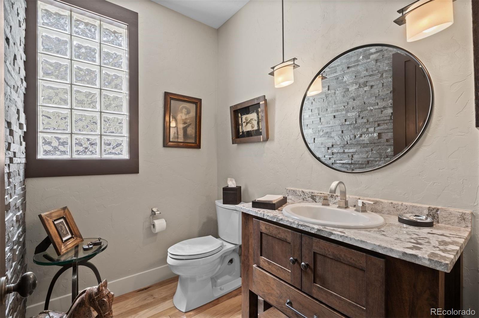1733 Swede Gulch Road Evergreen, CO 80439 - Photo 23 of 50 a bathroom with a granite countertop toilet a sink and a mirror
