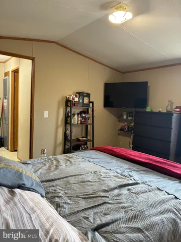 a bedroom with a bed and a flat tv screen on dresser