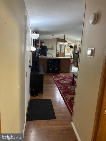 a living room with stainless steel appliances furniture a rug and a view of kitchen