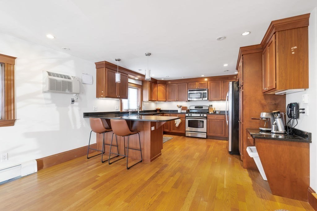 200 Washington Street Boston, MA 02135 - Photo 5 of 27 a kitchen with stainless steel appliances wooden floors stove top oven and sink