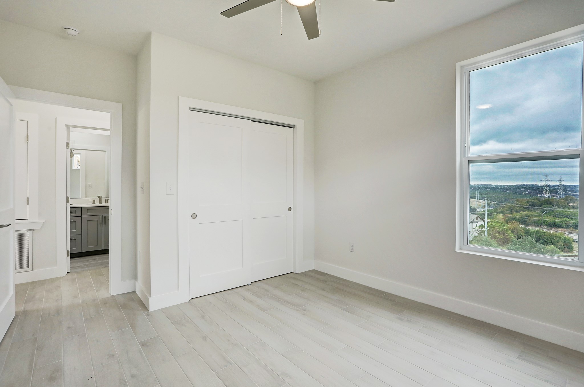4300 Mansfield Dam Road, Unit 531 Austin, TX 78734 - Photo 14 of 32 A bright window framing neighborhood views highlights this modern bedroom with wood-look tile flooring.