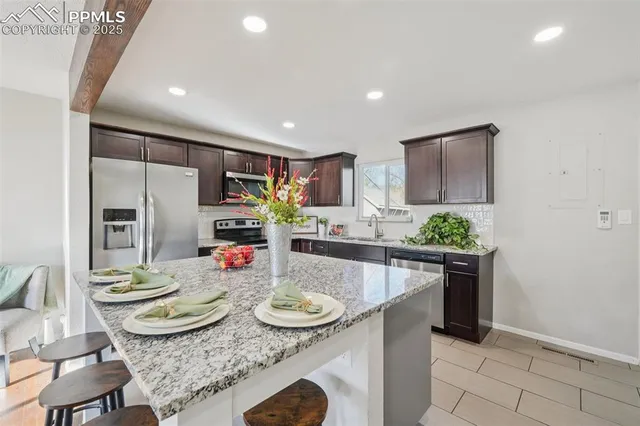 a kitchen with stainless steel appliances granite countertop a stove a sink a microwave a dining table and chairs