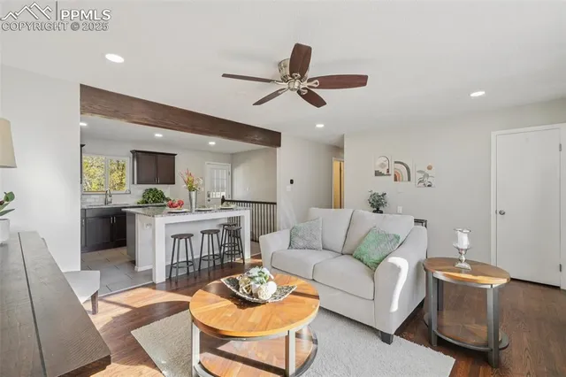 a living room with furniture kitchen view and a wooden floor