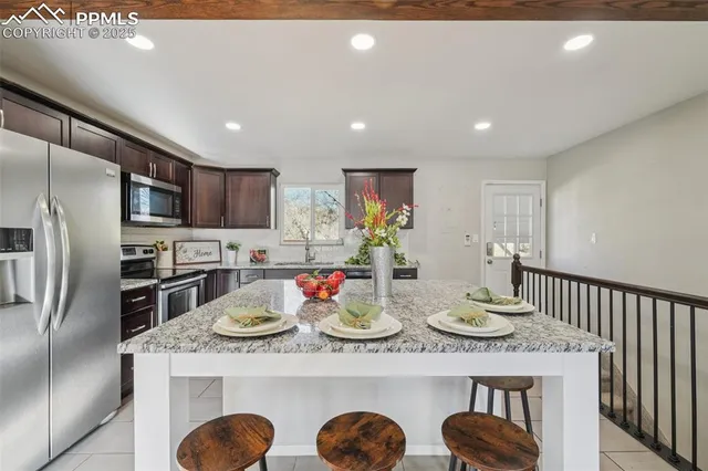 a kitchen with kitchen island granite countertop a stove refrigerator and microwave