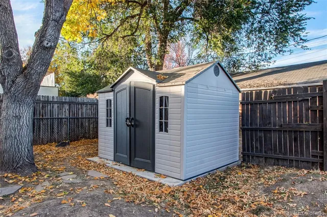 a view of a small house with wooden fence and a large tree